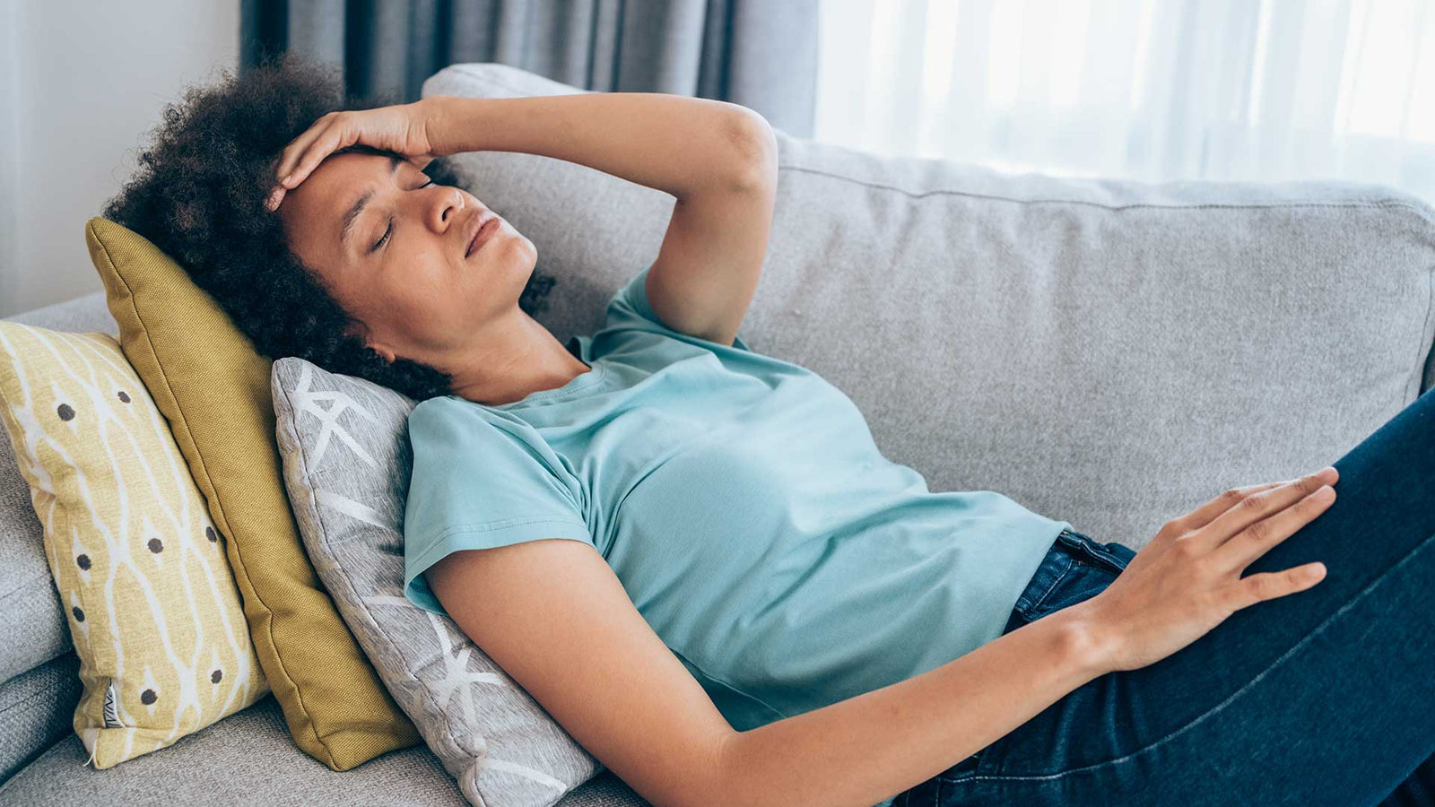 Woman lying on couch holding her head in pain
