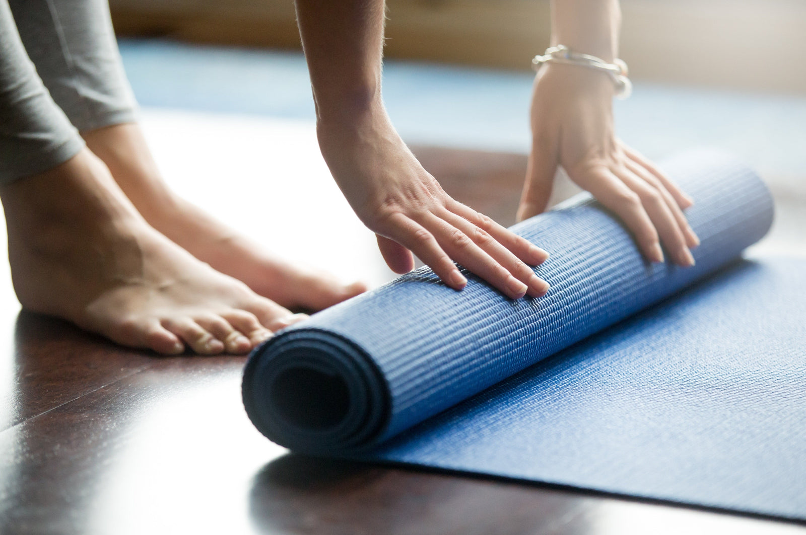 Woman rolling out blue yoga mat