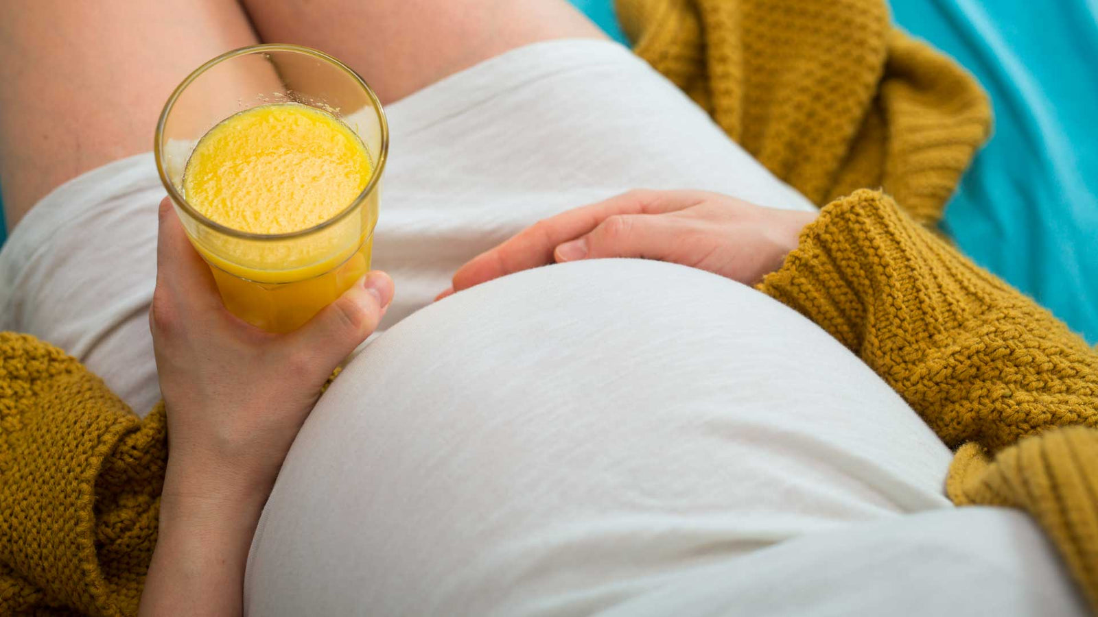 Pregnant woman lying down drinking orange juice