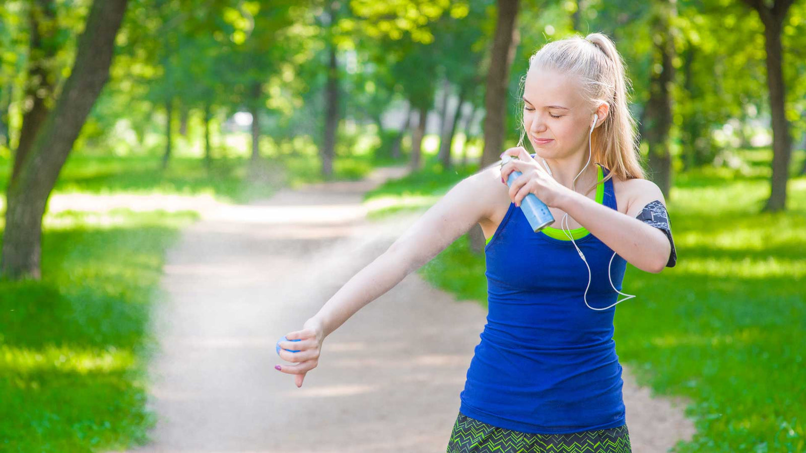 Woman in park spraying sun protection on arm