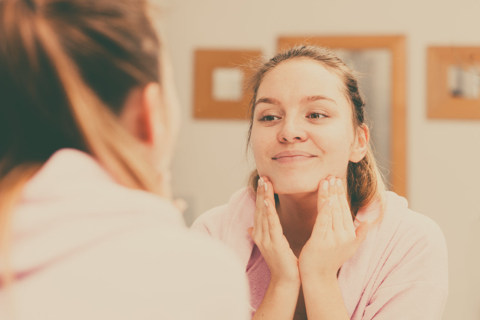 Woman touching both hands to chin in the mirror