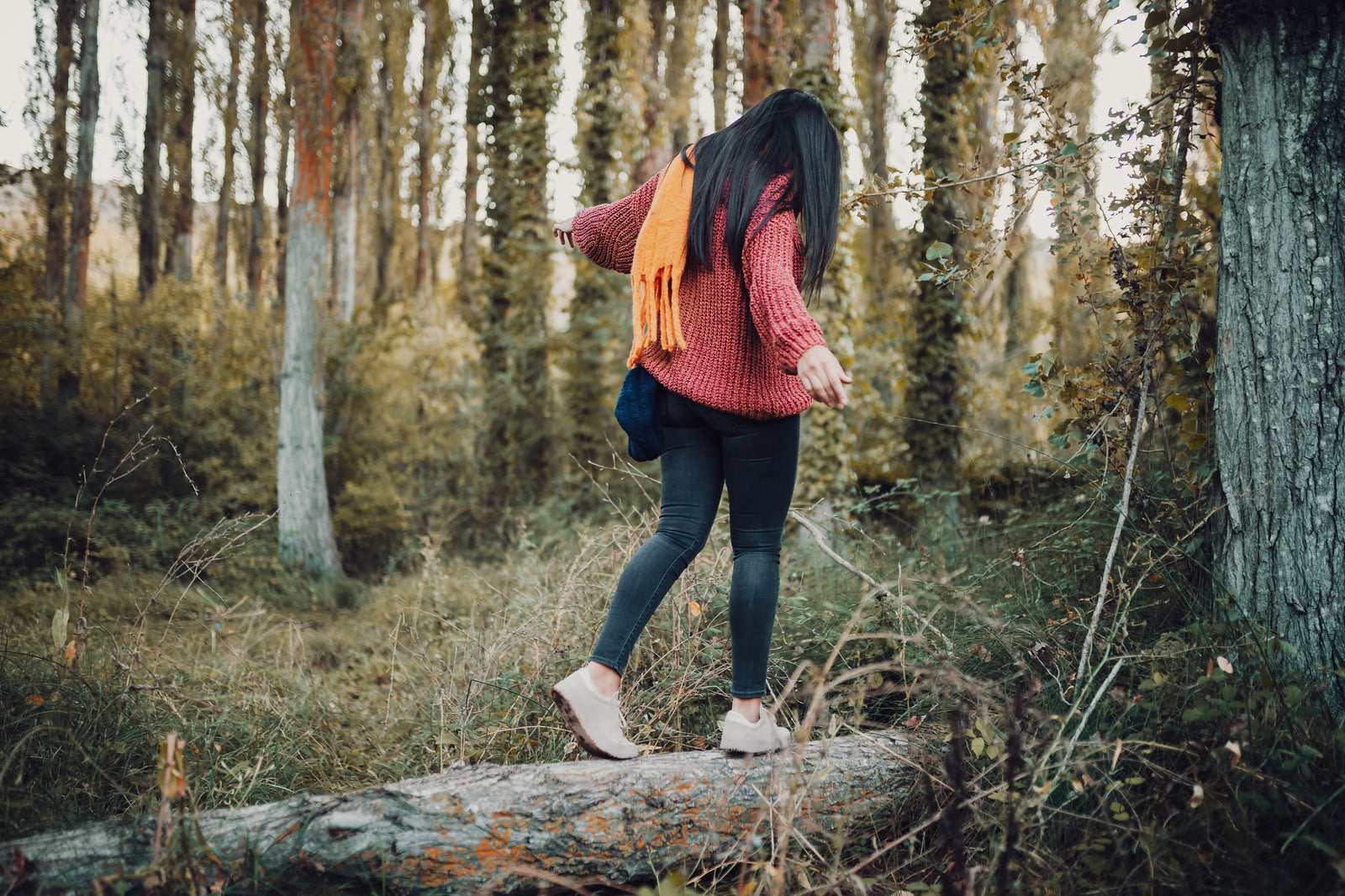 Woman in red jumper walking along a fallen tree