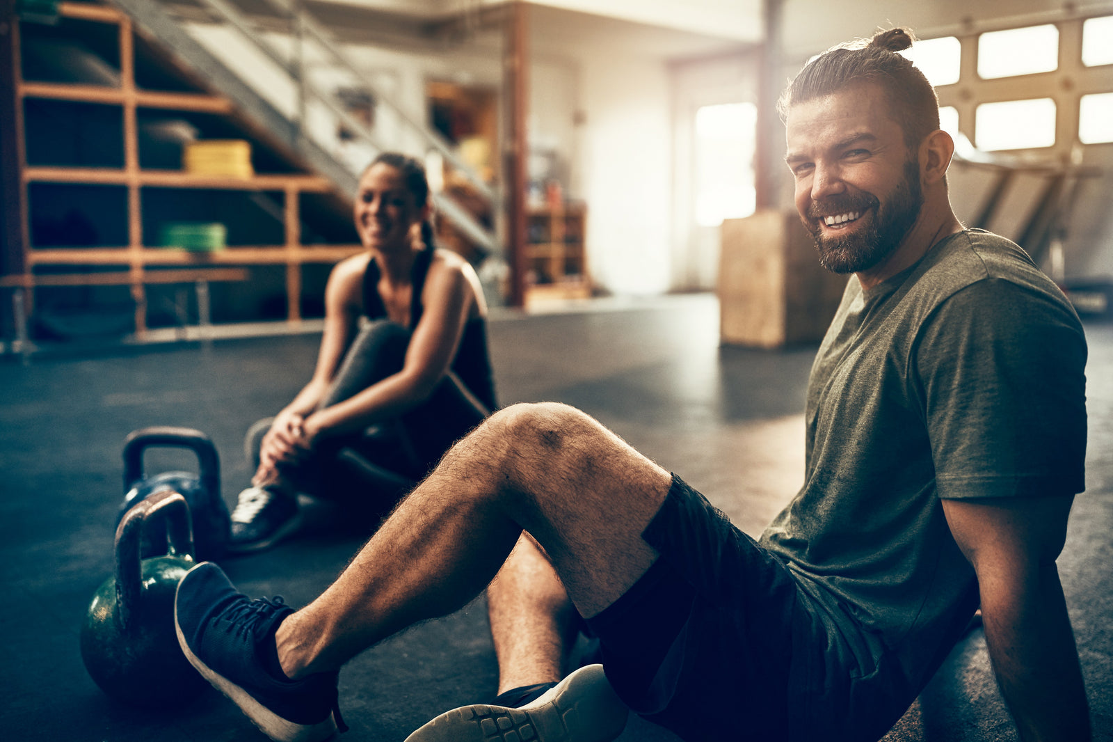 Man and woman in gym clothes sat on the floor in a gym