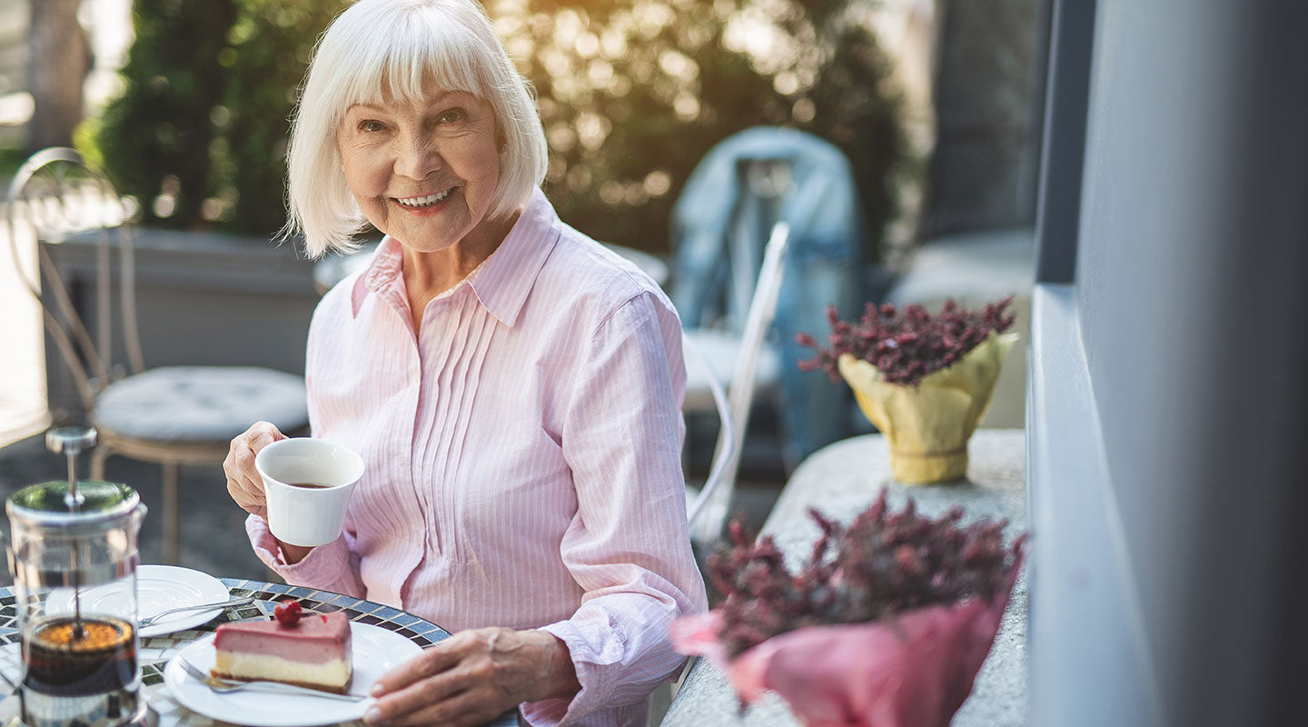 Old woman eating cake in a cafe garden