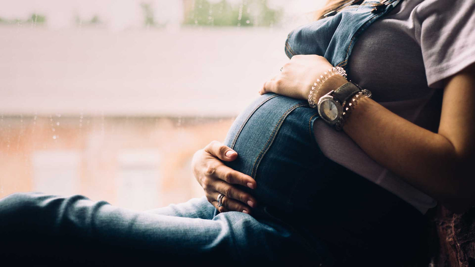 Pregnant woman sitting down holding her belly