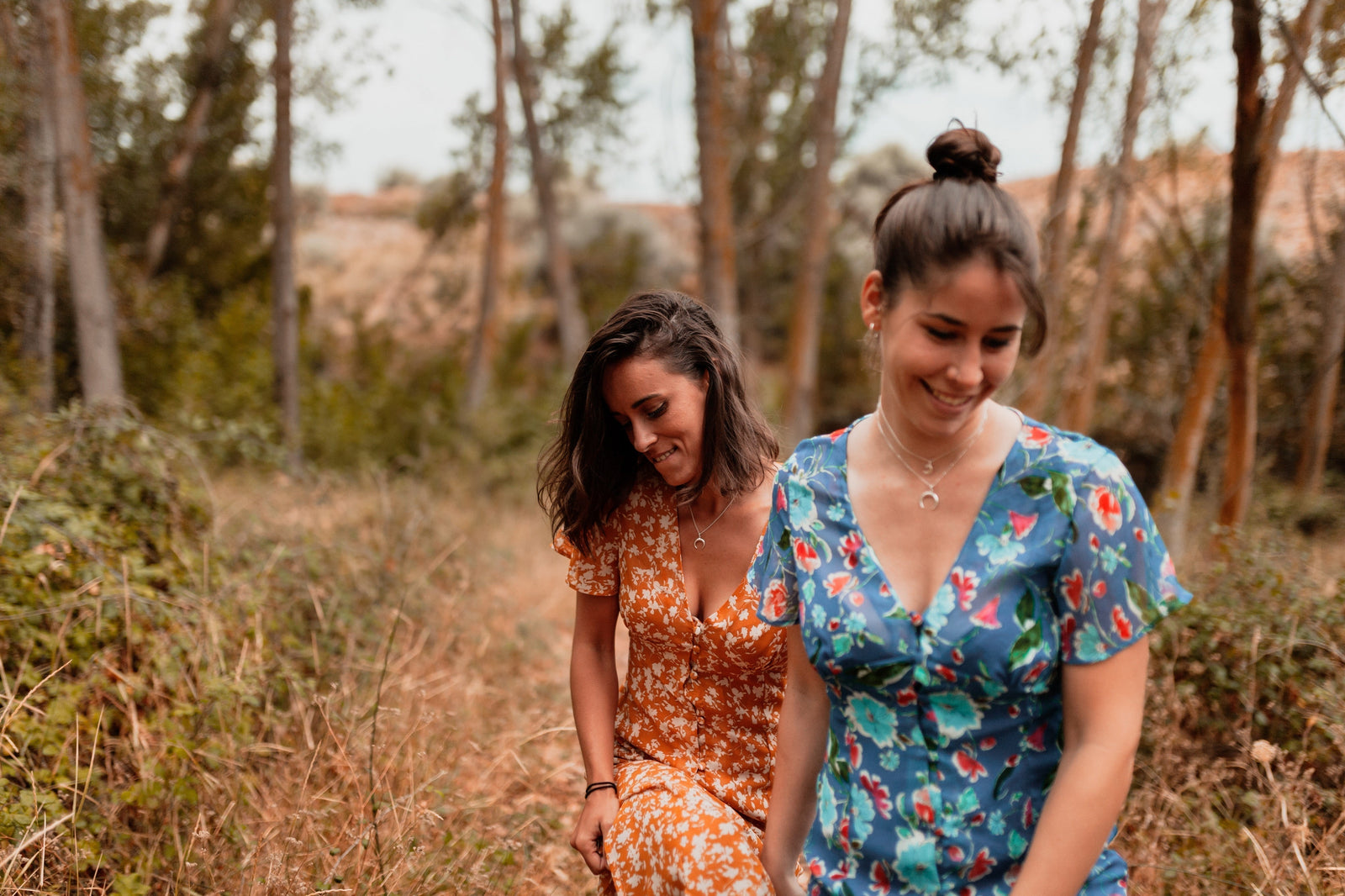 Two women in summer dresses on a woodland walk