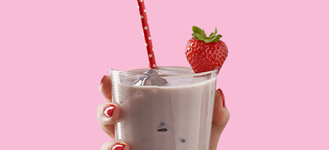 Hand holding strawberry SlimFast shake